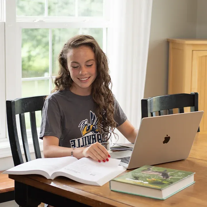 High school 学生 studying with laptop and books at kitchen table